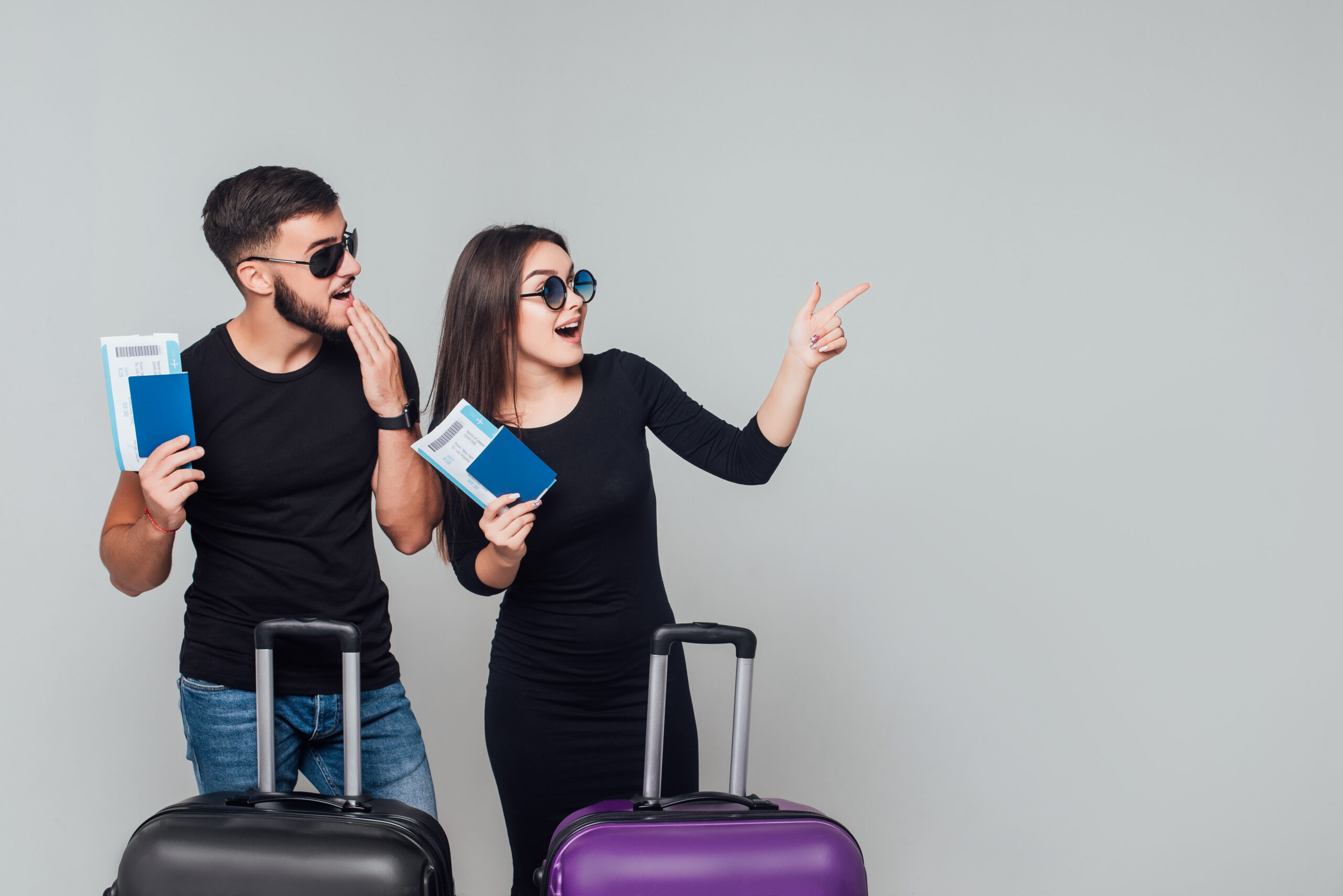 Smiling young happy couple with  suitcases and ticket around isolated on white background. Copy space. Place for some text.